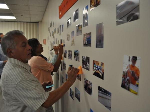 people writing on sticky notes on wall of photographs